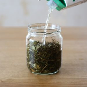 どくだみ乾燥葉を入れた容器にお酒をそそぐ