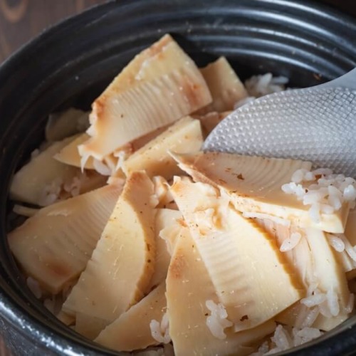 土鍋に入った筍ご飯をしゃもじで混ぜている。