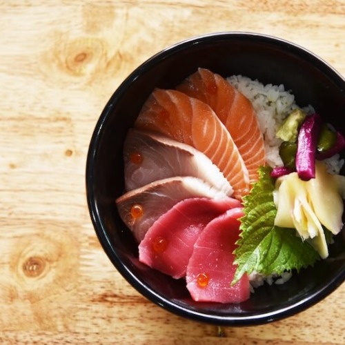 酢飯の上にサーモン、カンパチ、マグロ、しそなどがのっている海鮮丼