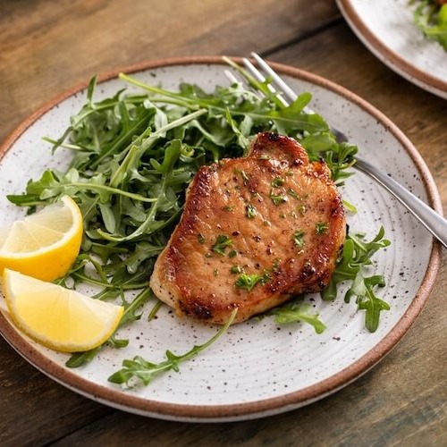 お酢でマリネした豚肉のステーキがサラダと共にお皿に盛り付けられている