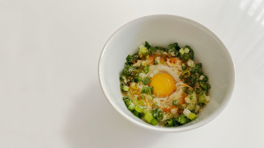 そうめんに卵黄、ネギ、ごま油などがかかっている。