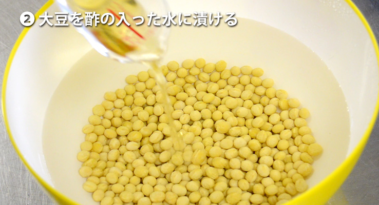 大豆を酢の入った水に漬ける